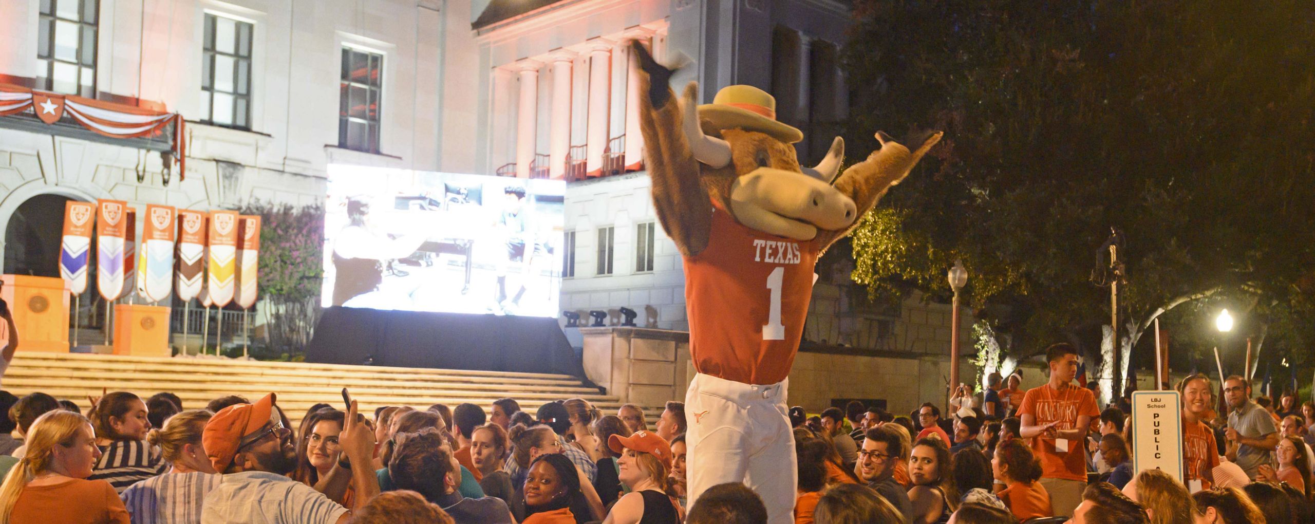 UT mascot, Hook 'em, in crowd at Gone to Texas with both arms raise igniting the crowd